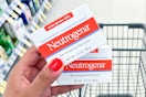 hand holding two boxes of Neutrogena facial bars in front of shopping cart