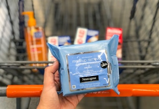 hand holding up neutrogena makeup wipes in front of shopping cart