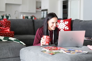 a woman holding a coffee mug and shopping on laptop
