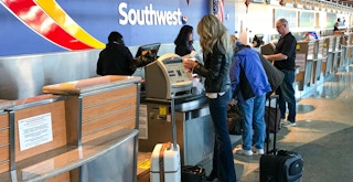 A person standing at the Southwest airlines check in desk at the airport