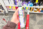 person holding herbal essences mousse over a cart