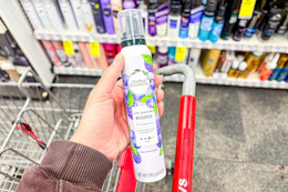 person holding herbal essences mousse over a cart