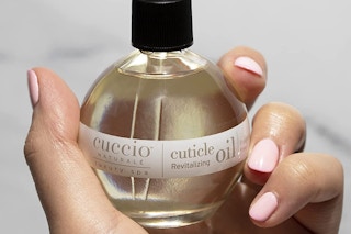 A hand holding a cuticle oil bottle