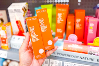 hand holding two orange boxes of Pacifica Baby Serum