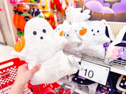 hand holding a ghost throw pillow at target