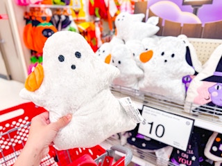 hand holding a ghost throw pillow at target