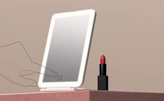 travel vanity mirror on a table with red lipstick