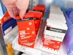 hand grabbing neutrogena stubborn acne patches off a target shelf