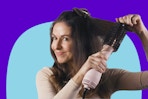 a woman blow drying her hair with a dryer brush