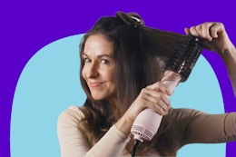a woman blow drying her hair with a dryer brush
