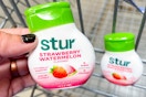 hand holding a bottle of stur liquid water enhancer over shopping cart
