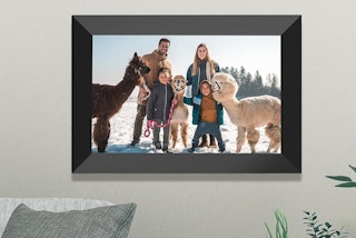 a digital picture frame on a wall with a family and alpacas