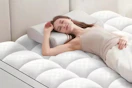 a woman laying on a mattress pad