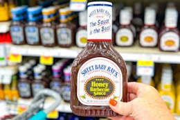 hand holding a bottle of sweet baby rays bbq sauce