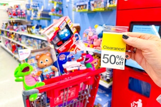 hand holding target clearance sign in front of a cart full of discounted toys