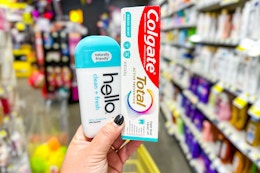 hand holding hello deodorant and colgate toothpaste