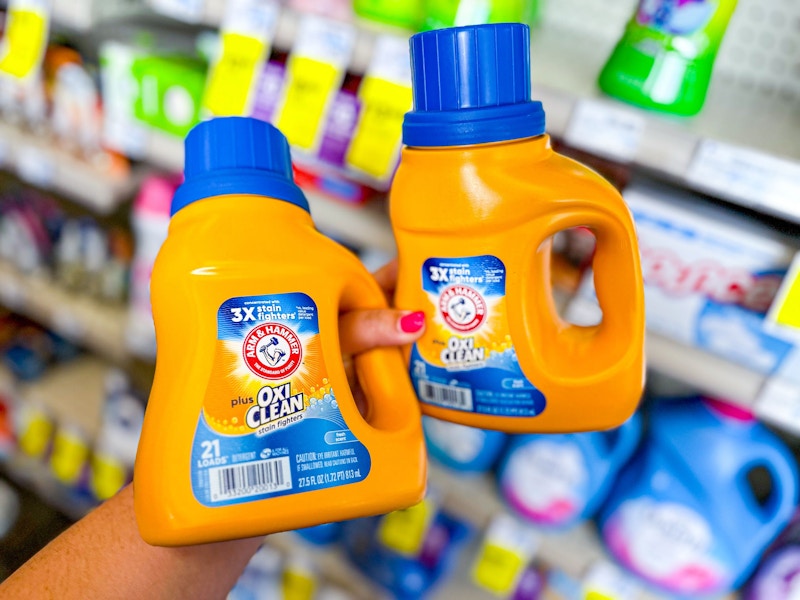 person holding 2 jugs of arm and hammer detergent
