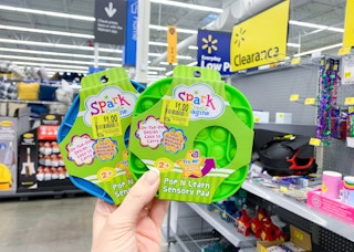 two spark create imagine pop n learn sensory pad held up in front of walmart clearance sign