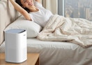 a air purifier on a nightstand next to a person in a bed