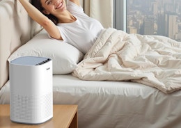 a air purifier on a nightstand next to a person in a bed