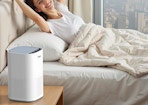 a air purifier on a nightstand next to a person in a bed