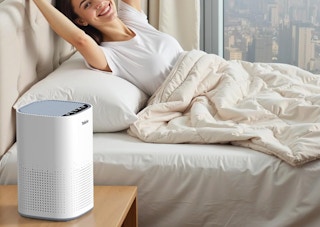 a air purifier on a nightstand next to a person in a bed