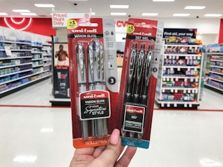 hand holding 2 packs of uni-ball pens at target