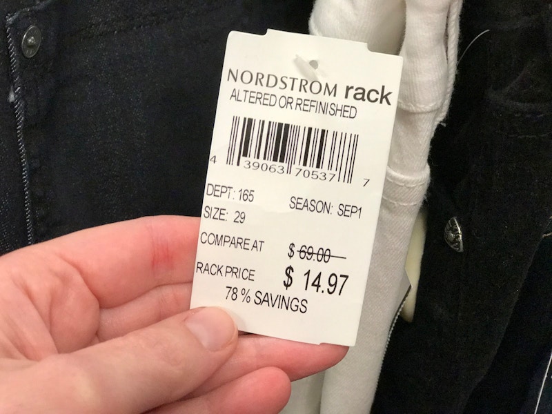 A person holding a price tag that says "Nordstrom Rack Altered or Refinished".