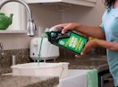 a person pouring cleaning solution in a bucket in a sink