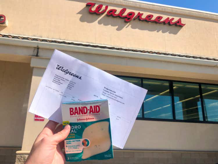 Person holding product and printed receipt in front of Walgreens store