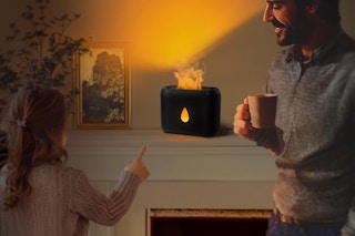 A child and a man stand on either side of the flame diffuser, which is on the mantel.