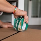 a person taping up a box with a roll of tape 