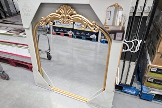 a large gold framed mirror in a box