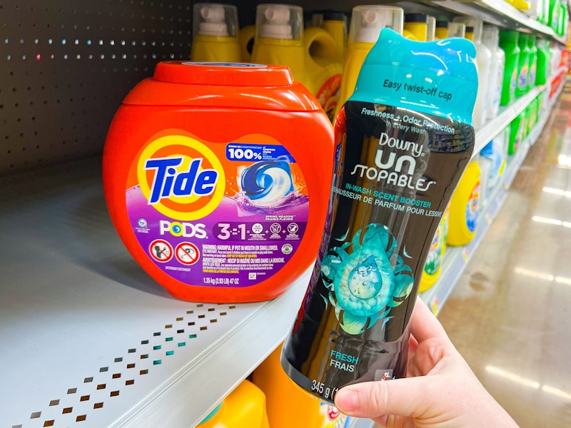 tide pods on a shelf with a person holding downy unstoppables near it