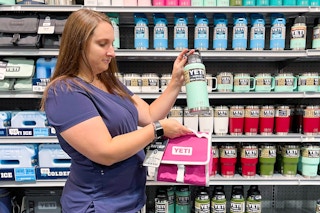 A first responder in scrubs holding YETI items in a store.