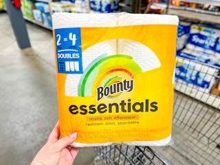 hand holding 2-pack of Bounty paper towels over a shopping cart in a store aisle