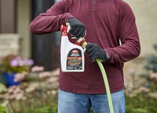 a person holding a bottle of insect killer spray outside