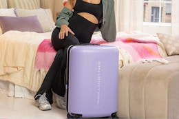 person sitting on bed next to luggage