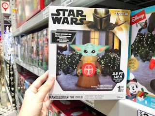 hand grabbing baby yoda inflatable in box on store shelf