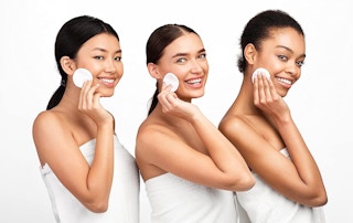 three women holding cotton rounds on their face