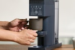 person grabbing cup from Chefman coffee maker 