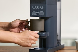 person grabbing cup from Chefman coffee maker 