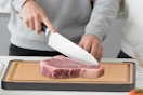 a man cutting meat on a cutting board