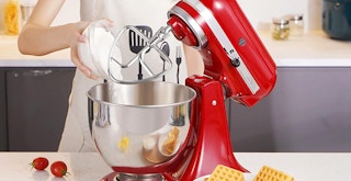 best kitchenaid mixer attachments - person using red stand mixer with accessories in kitchen