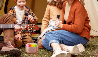 a family sitting on grass with a mini karaoke machine