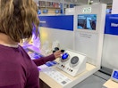 A woman testing out a Nest thermostat on the Nest display inside Best Buy.
