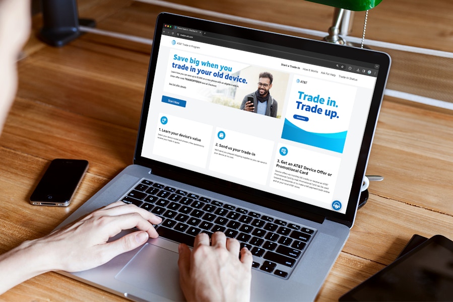 someone looking at the AT&T trade in webpage with devices on the table