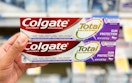 hand holding two boxes of Colgate Total toothpaste in the aisle