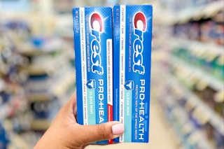 Hand holding two boxes of Crest Pro-Health toothpaste