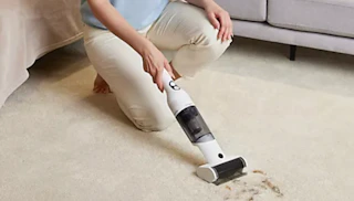 a person using a handheld vacuum on a carpet